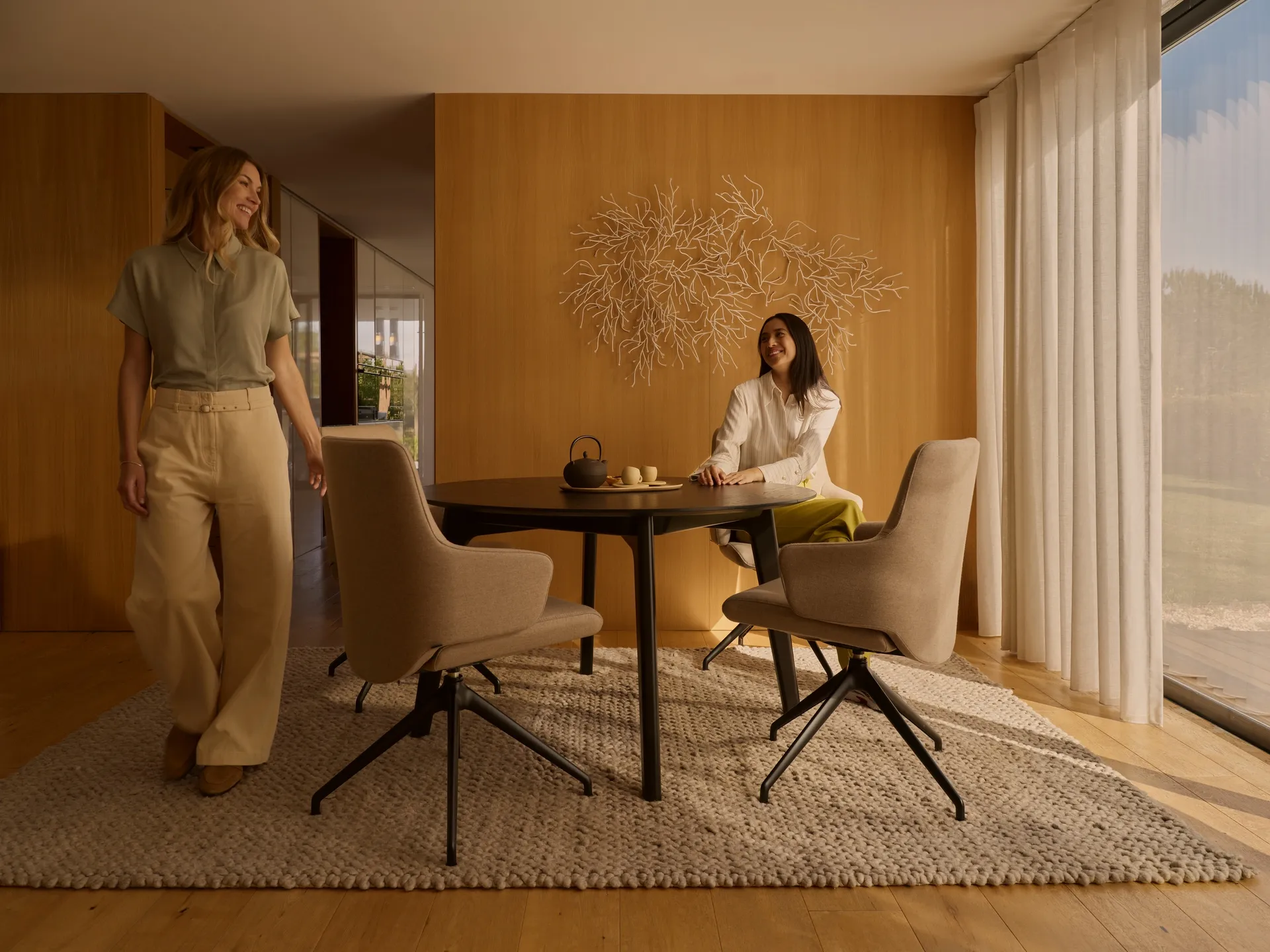 Two women laughing around a dining table which features Stressless Laurel dining chairs