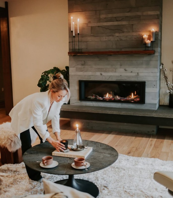 Woman leaning down to place a candle on a light grey table