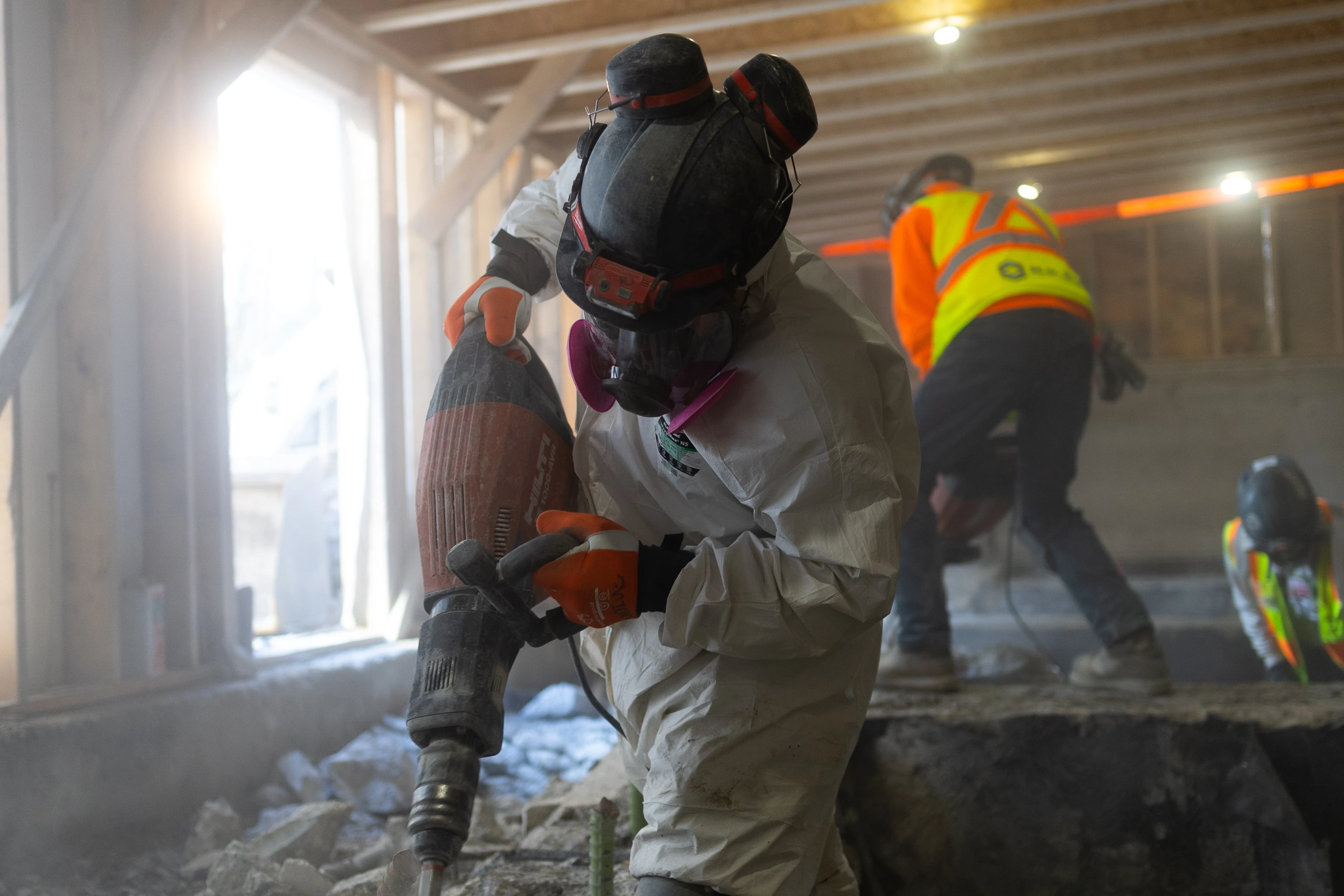 Construction worker using jackhammer for concrete demolition on Calgary commercial project