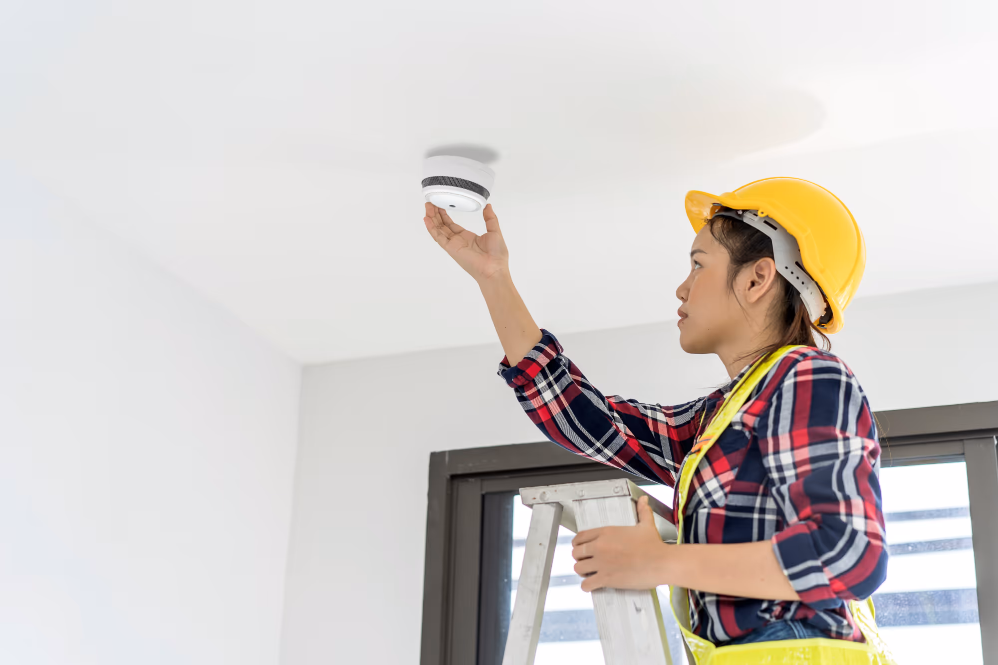 Woman installing smoke alarm. 