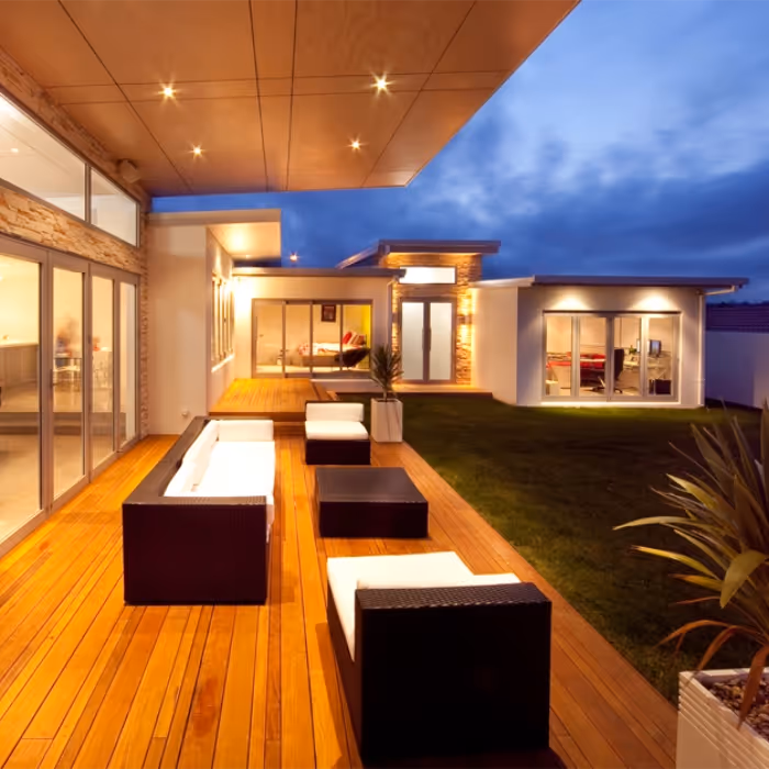 Outside of home with wooden deck and outdoor furniture. 