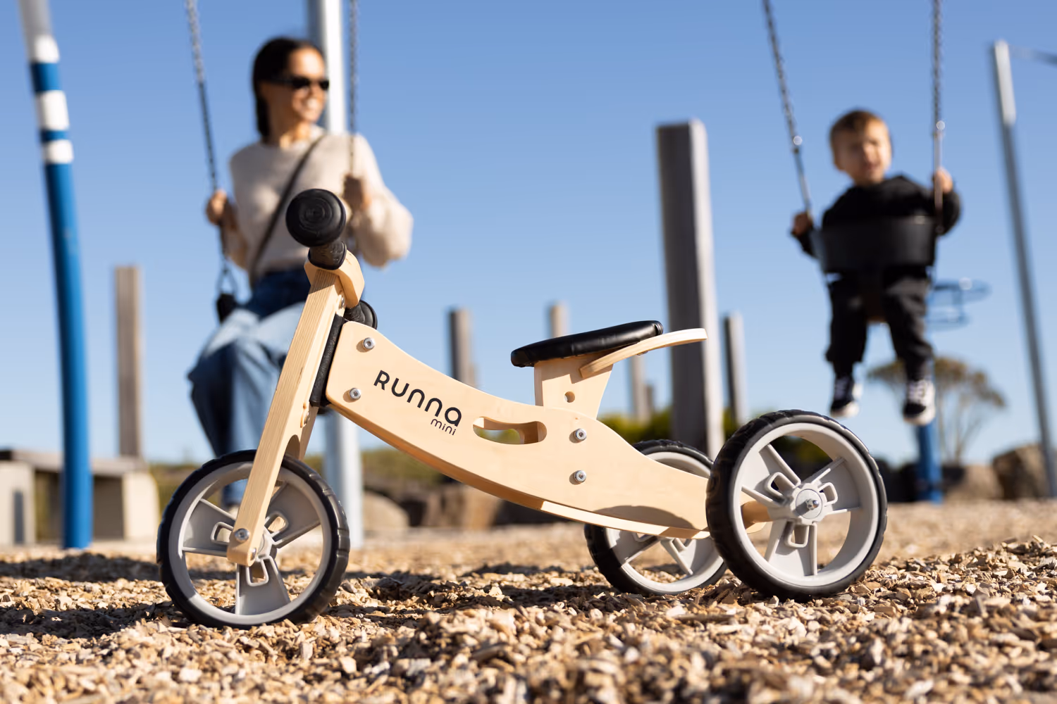 Wooden tricycle with mother and child behind them. 