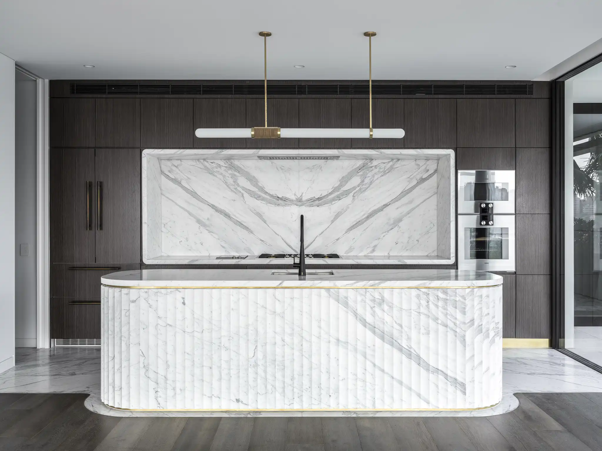 A white marble kitchen with fluted waterfall panels
