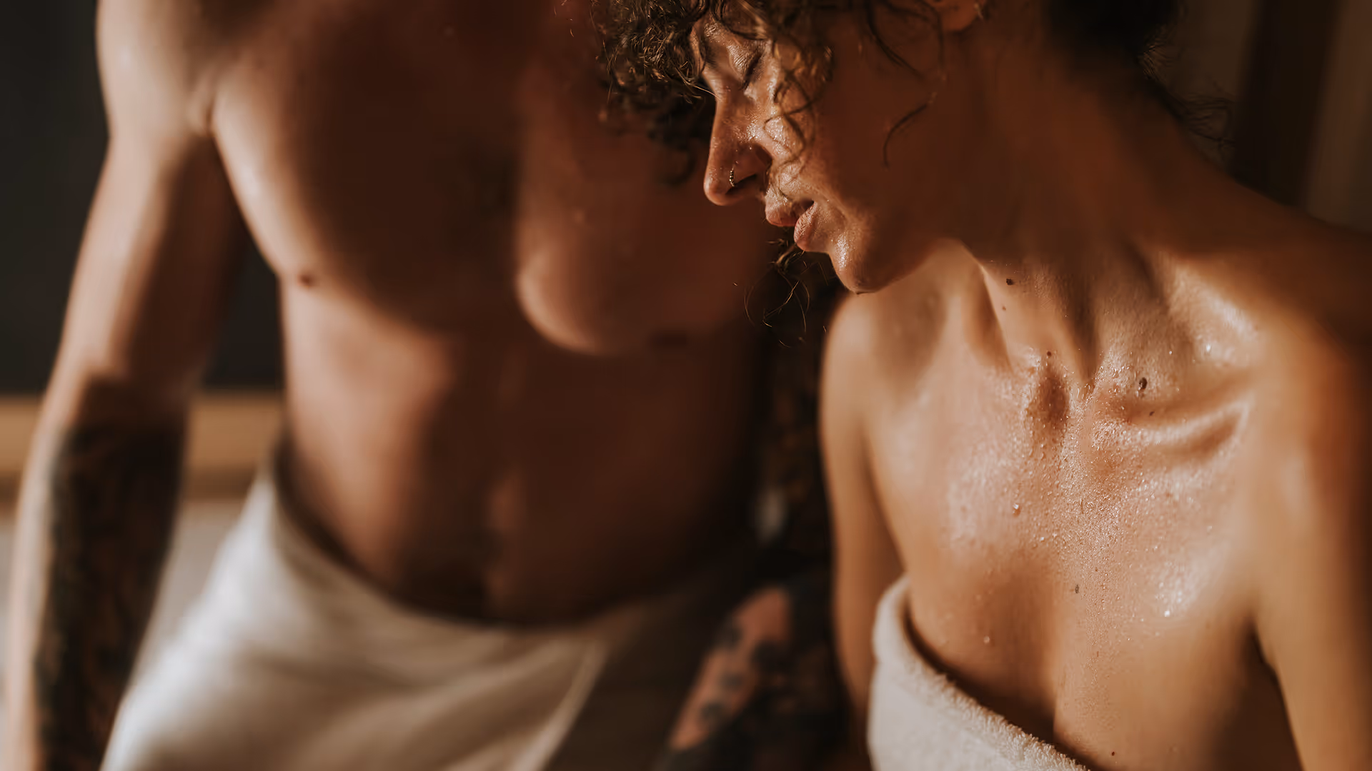 Couple in infrared sauna wearing towels in deep meditation