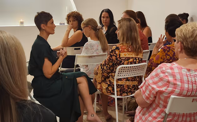 group sitting in chairs around a speaker