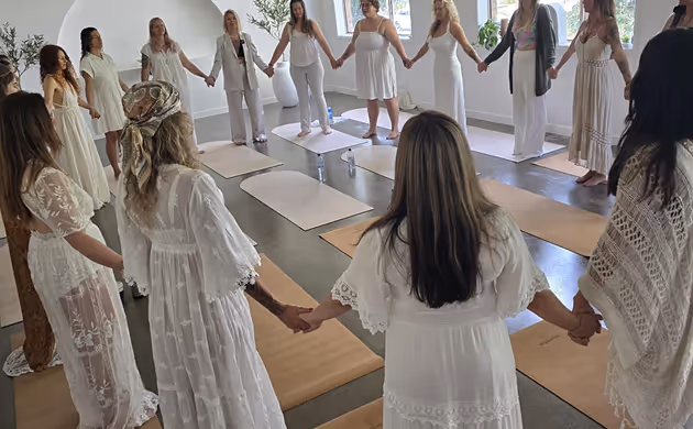 women holding hands in large circle inside