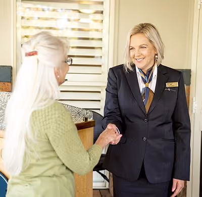 A funeral director shakes a woman's hand.