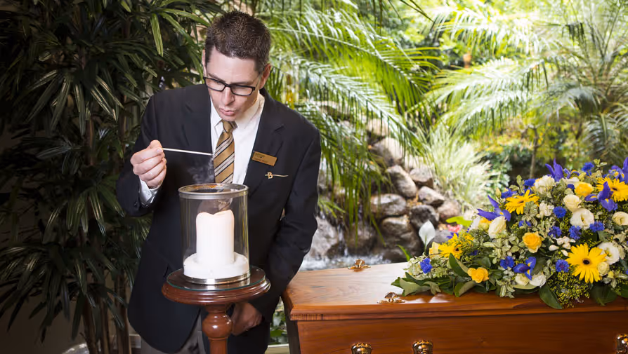 Funeral director lighting a memorial candle.