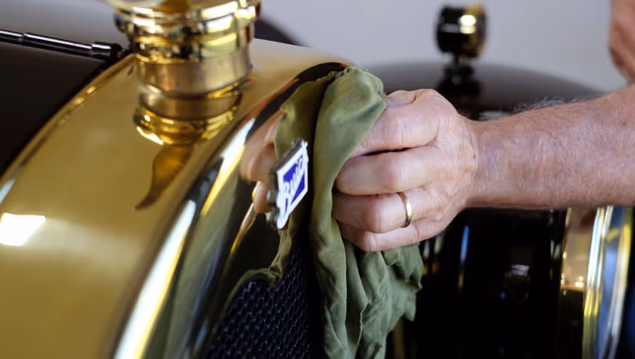 A hand polishing brass on a classic car.