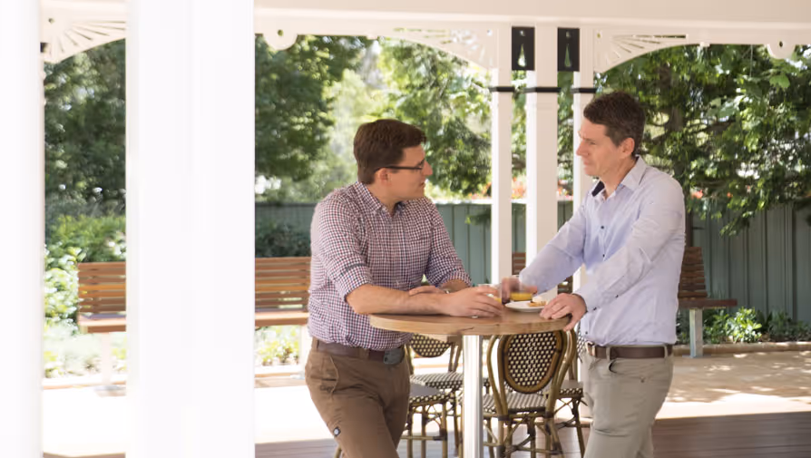 Two men talking in an outdoor gazebo.