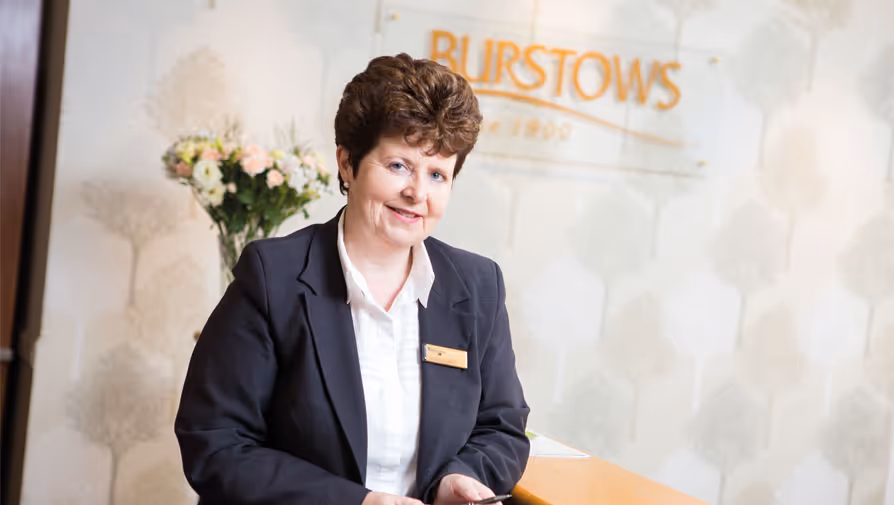 A smiling woman at a "Burstows" reception desk.