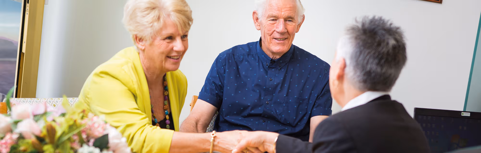 A smiling senior couple pre-planning a funeral with a director.