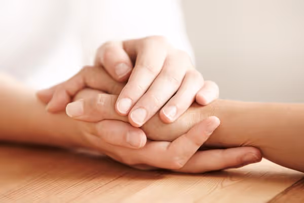 A supportive hand gently holding another hand, offering comfort.