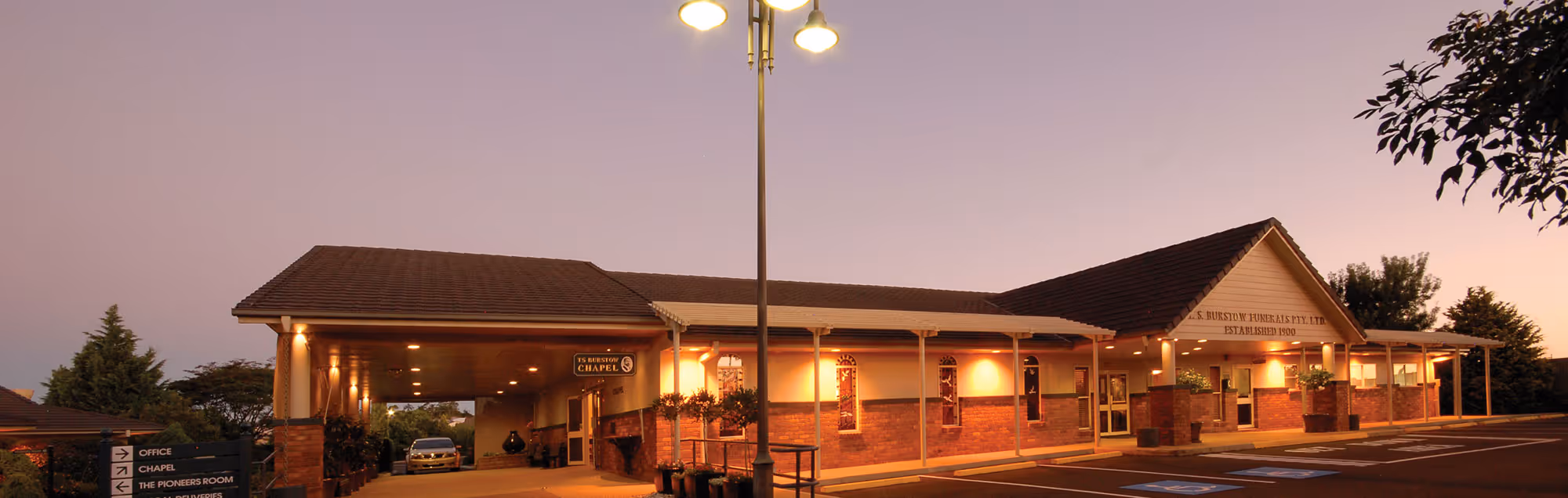 A grand funeral home building at dusk with soft lighting.