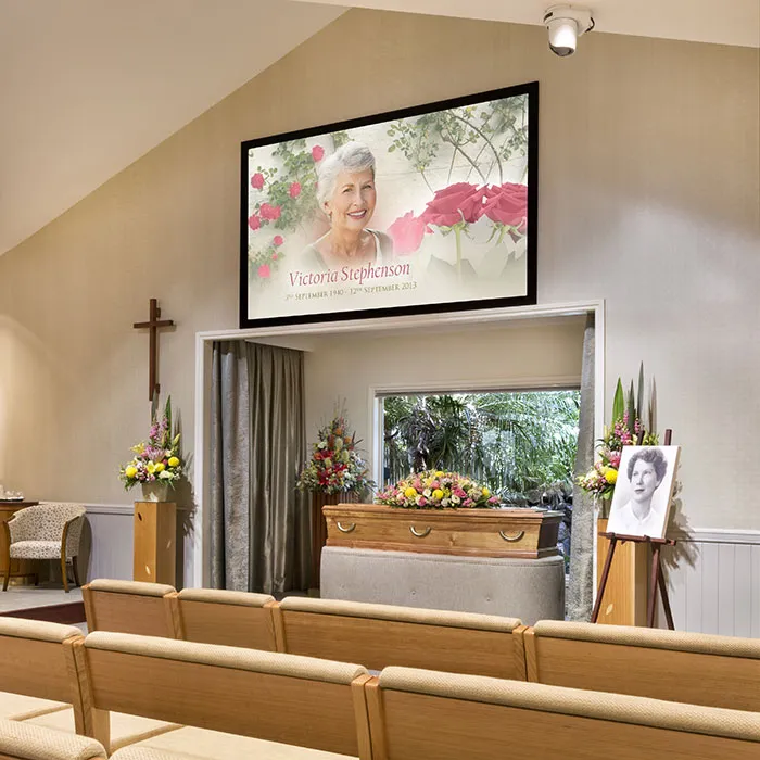 A funeral service with a casket and photo.