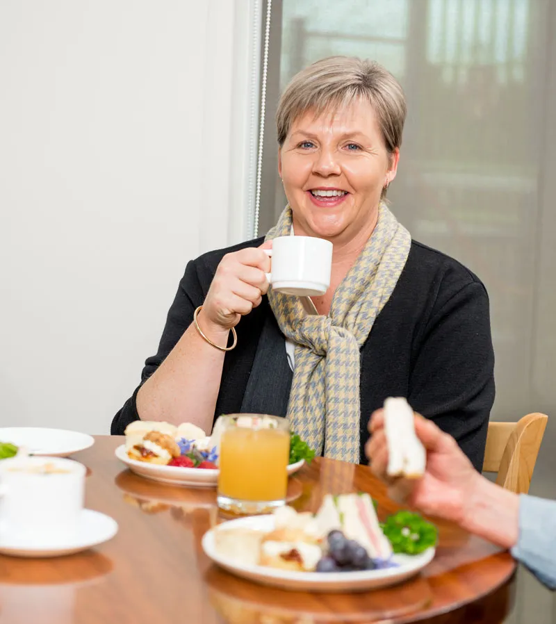 A woman enjoying tea and snacks at a table.