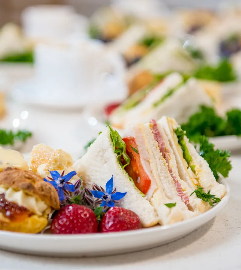 A plate with finger sandwiches and pastries.