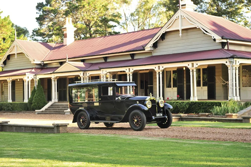Black vintage hearse parked in front of house.