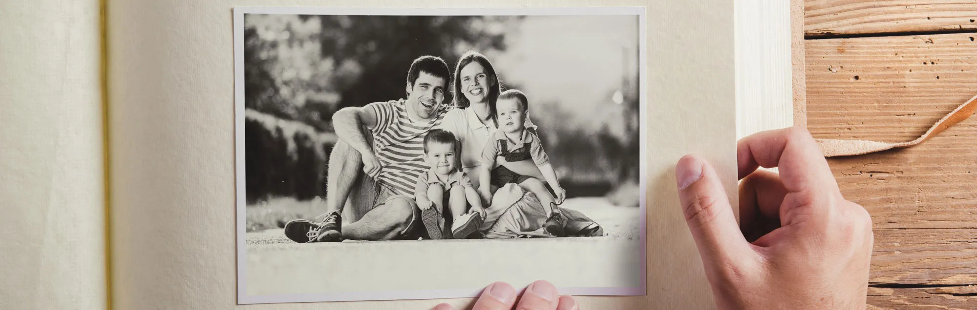 A pair of hands placing a black and white family photo into an album.
