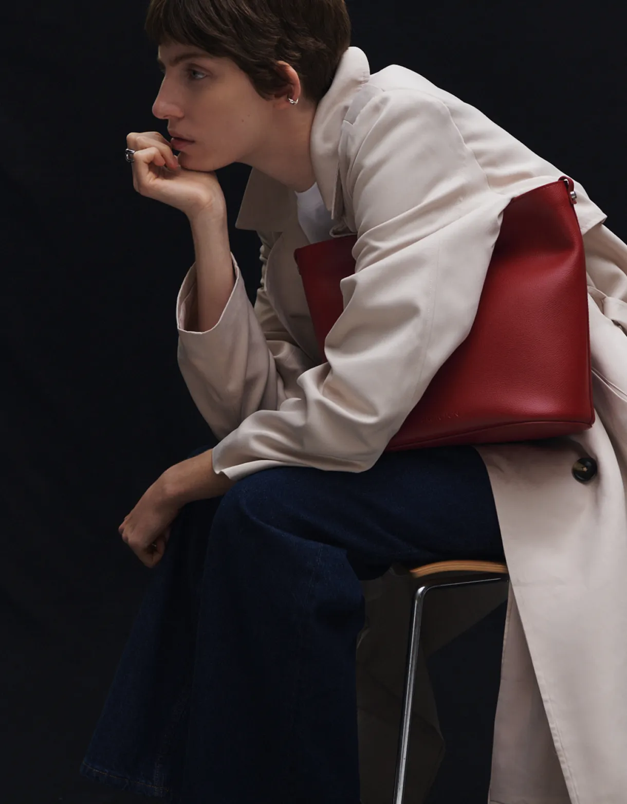 A woman wearing a red bag in front of a black wall