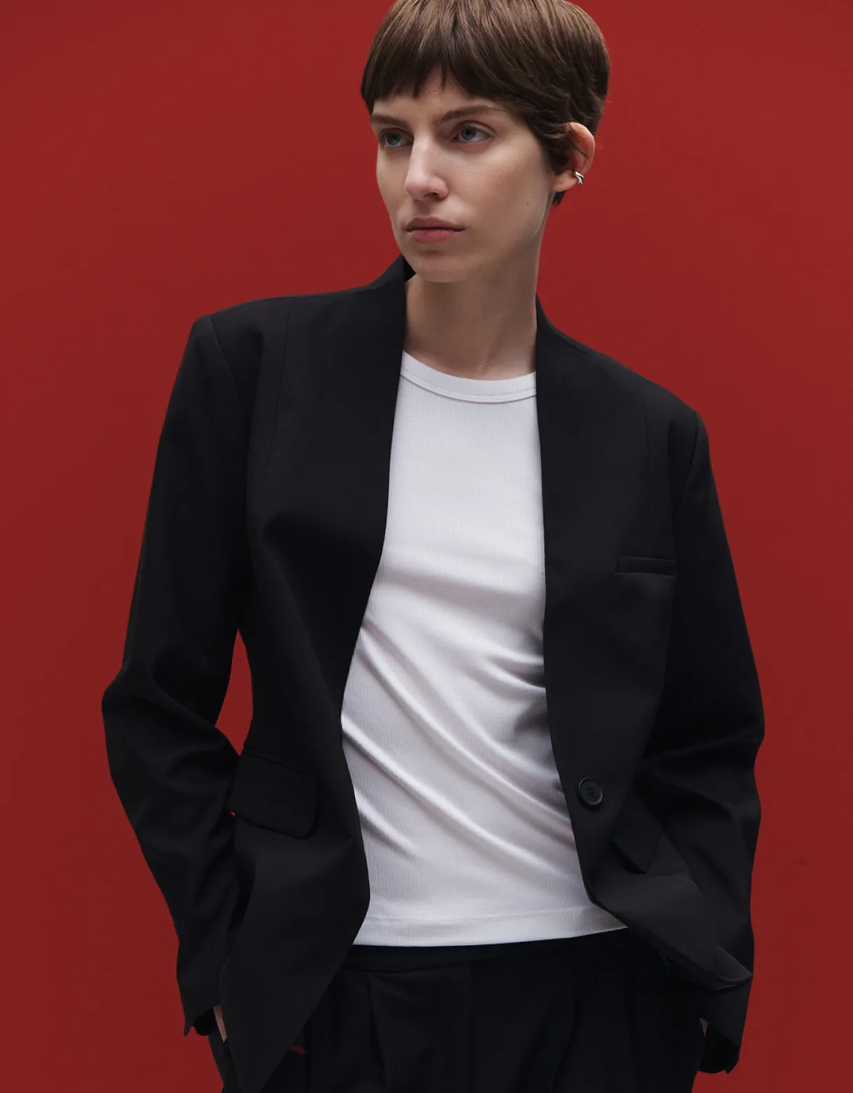 A woman wearing black and white fashion standing in front of a red wall