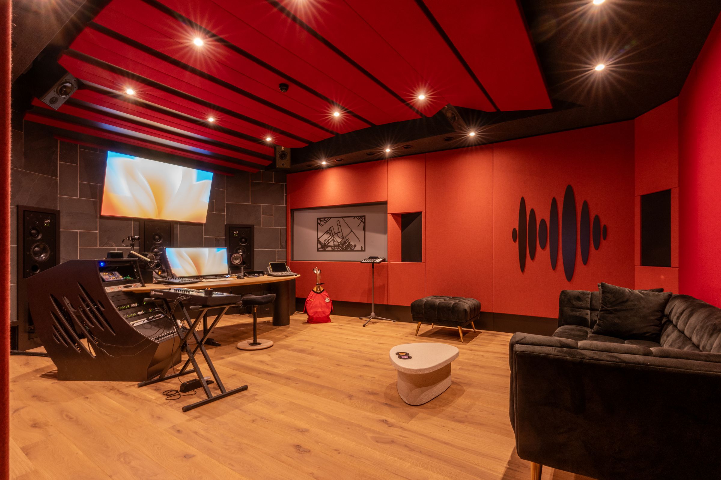 Studio 1 van TFA: de Dolby Atmos-studio in Amsterdam met rode akoestische wanden en plafond, regietafel, keyboard en een bank