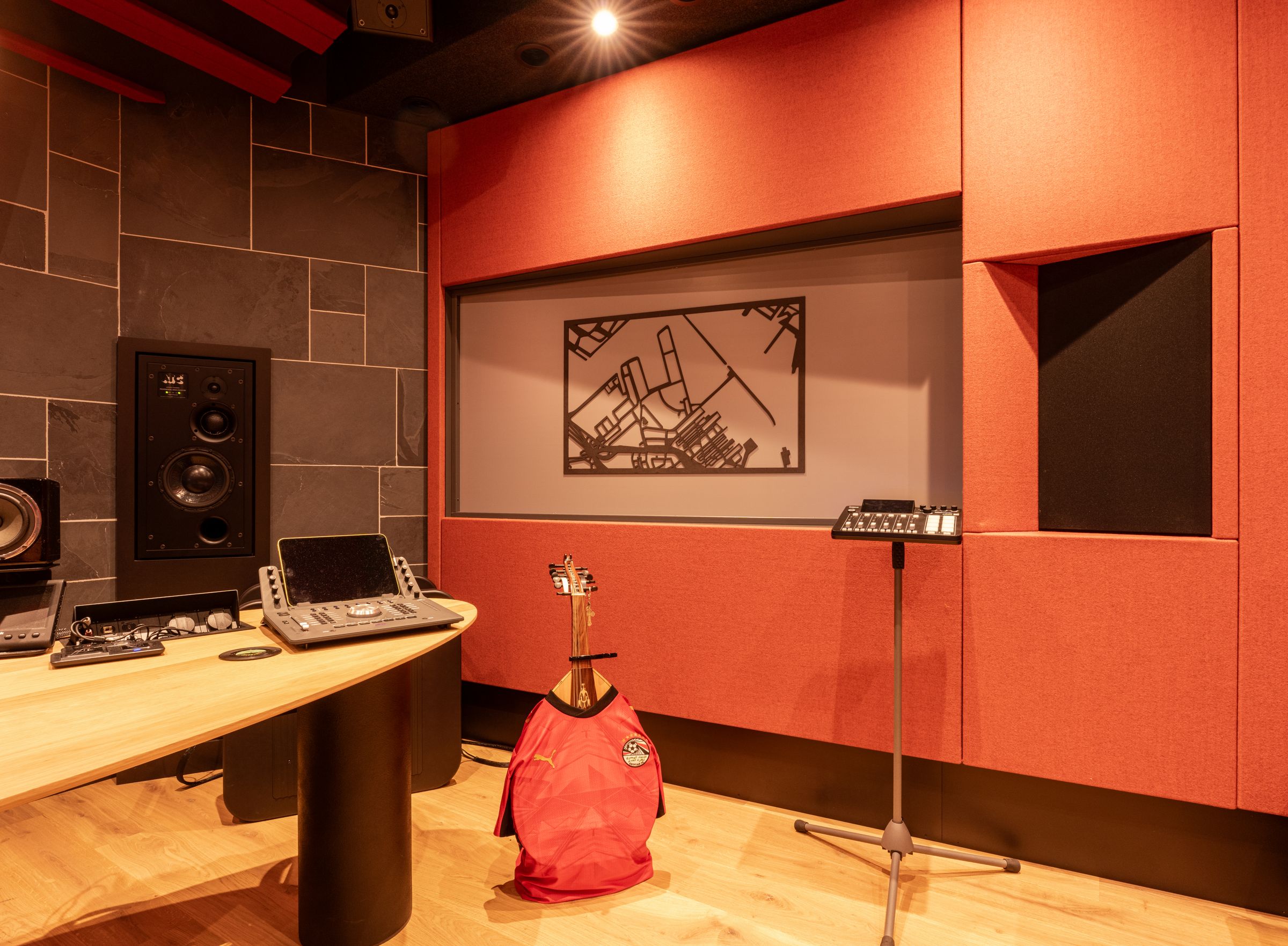 Studio 1 van TFA met rode akoestische wanden, een studiomonitor in de achterwand en audiosoftware op het scherm