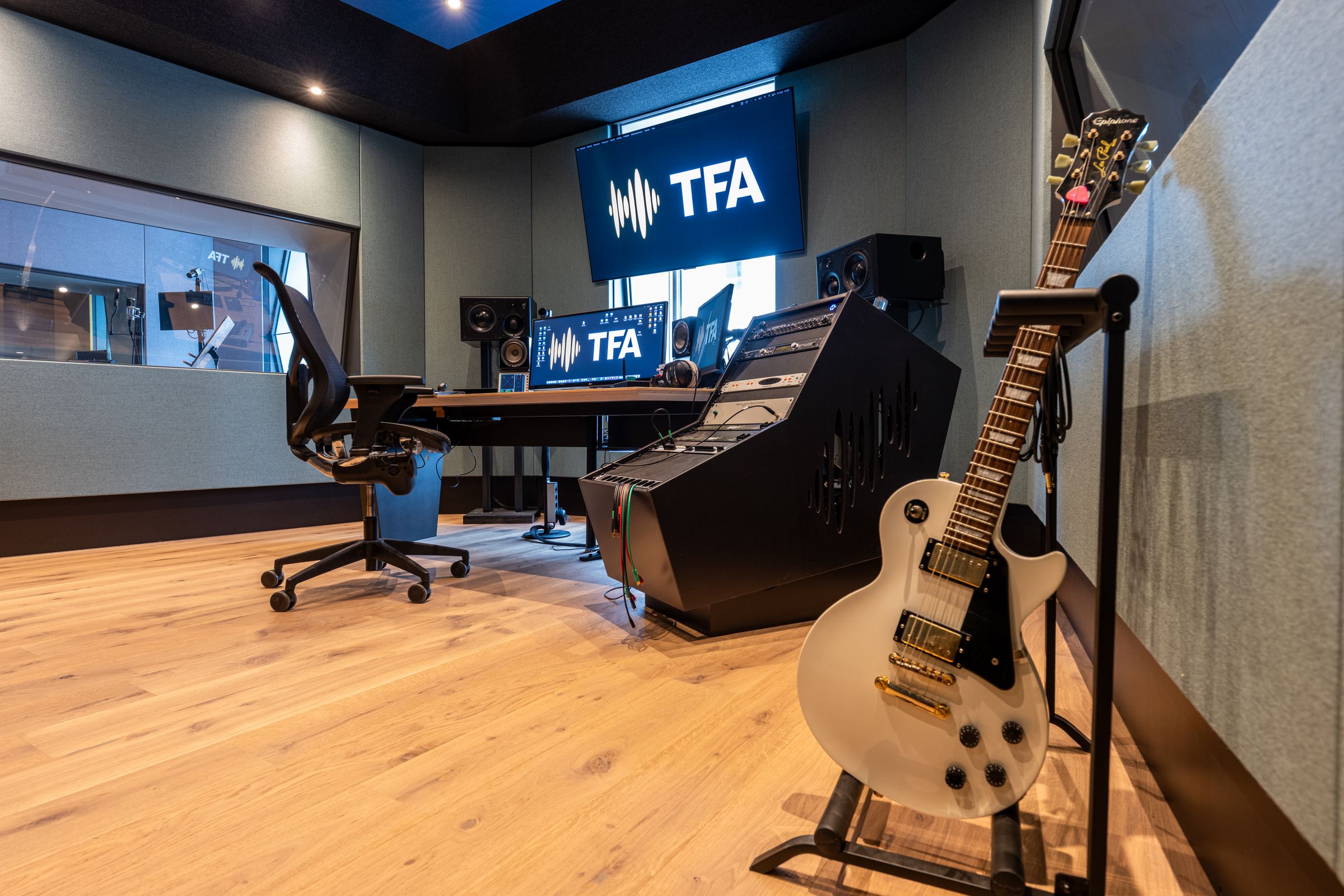 Studio 2 van TFA met petrolblauwe wanden, een keyboard, studiomonitoren en een bruine bank
