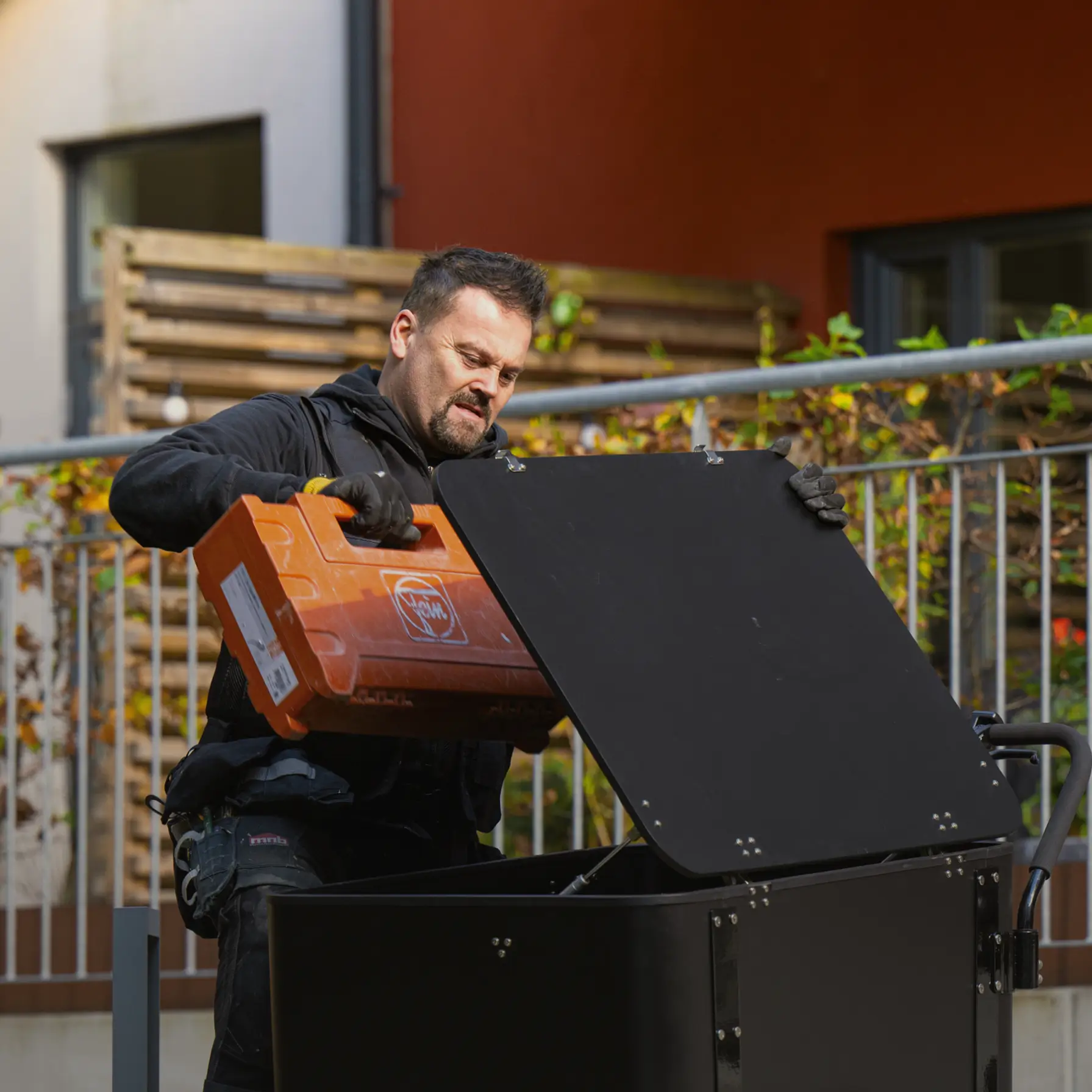 handyman with orange bag putting it in the cargobike