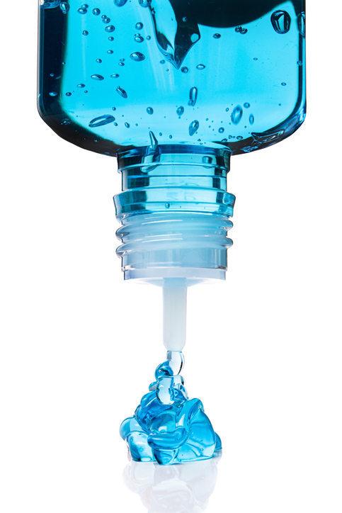 L’image présente un gros plan d’un flacon plastique transparent, retourné, en train de distribuer un gel bleu épais