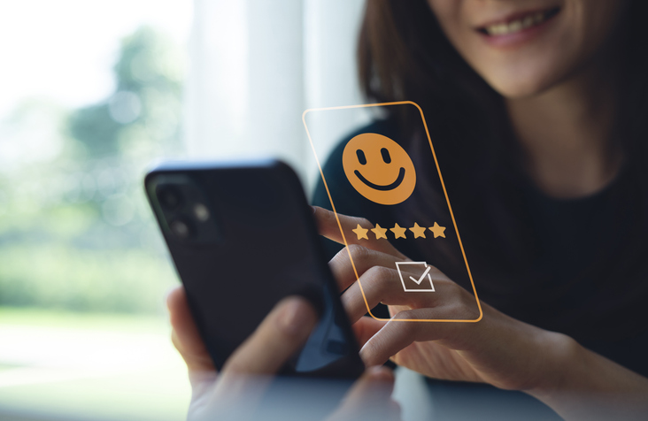 L’image montre une personne tenant un smartphone, en train d’interagir avec une interface digitale semi-transparente superposée à l’écran, relation client et CRM