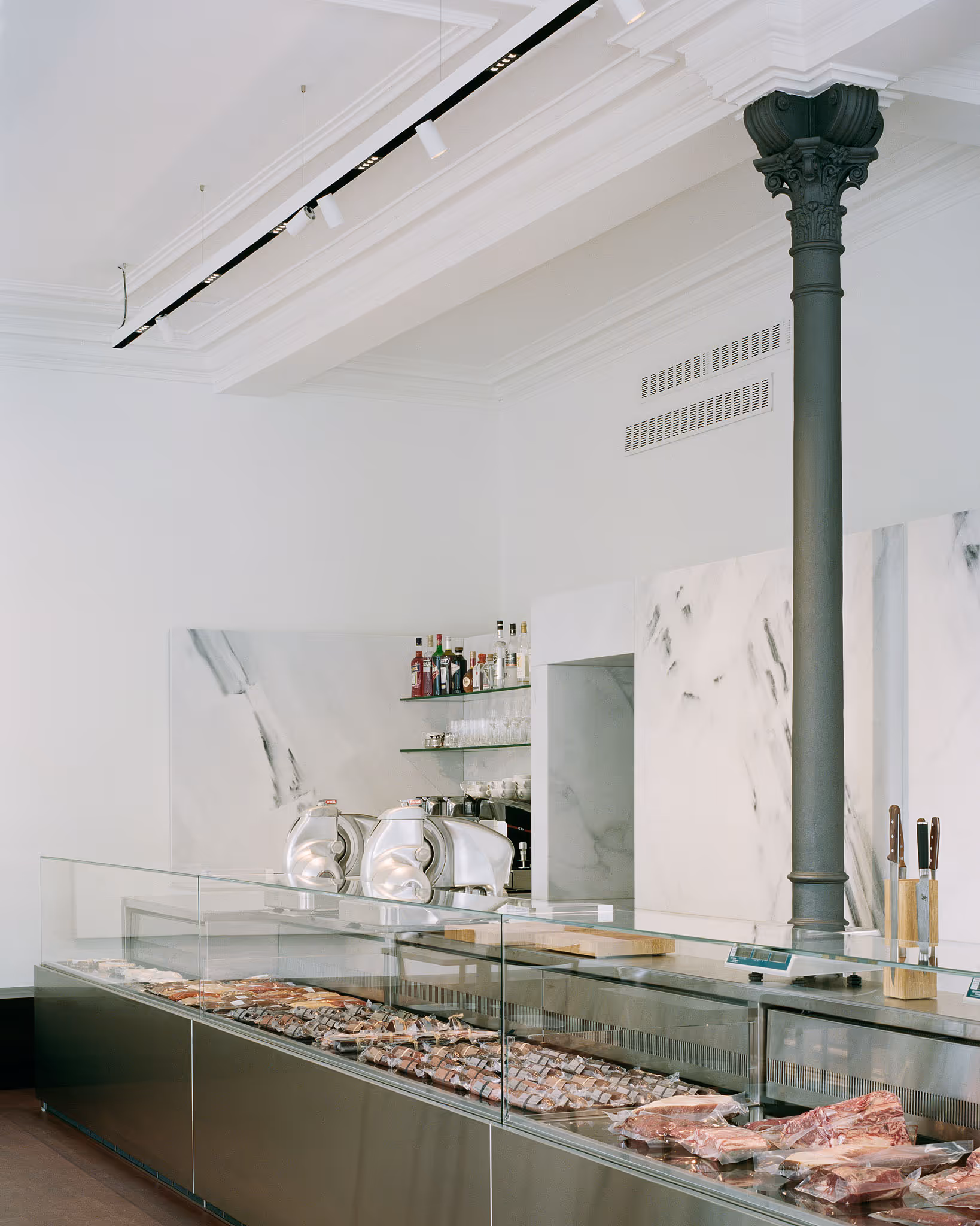 Metzgerei mit Fleischscheiben in Glasvitrine, elegante weiße Inneneinrichtung