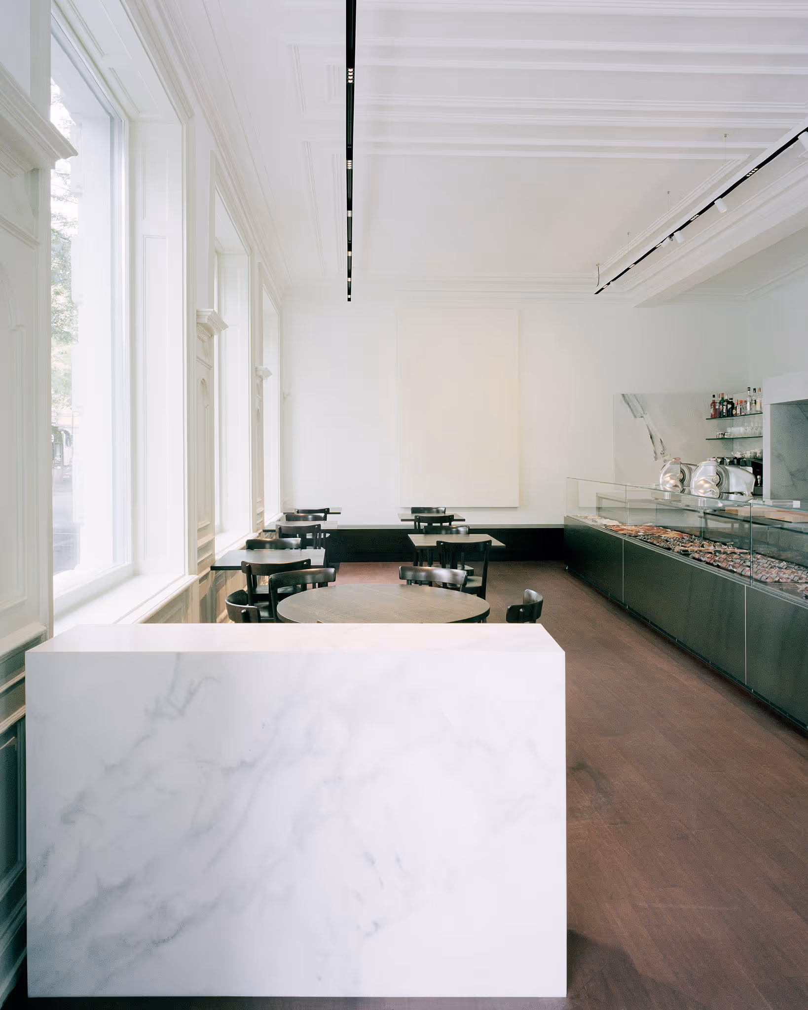 Minimalistisches Café mit grüner Theke, Holzboden und Fenstern