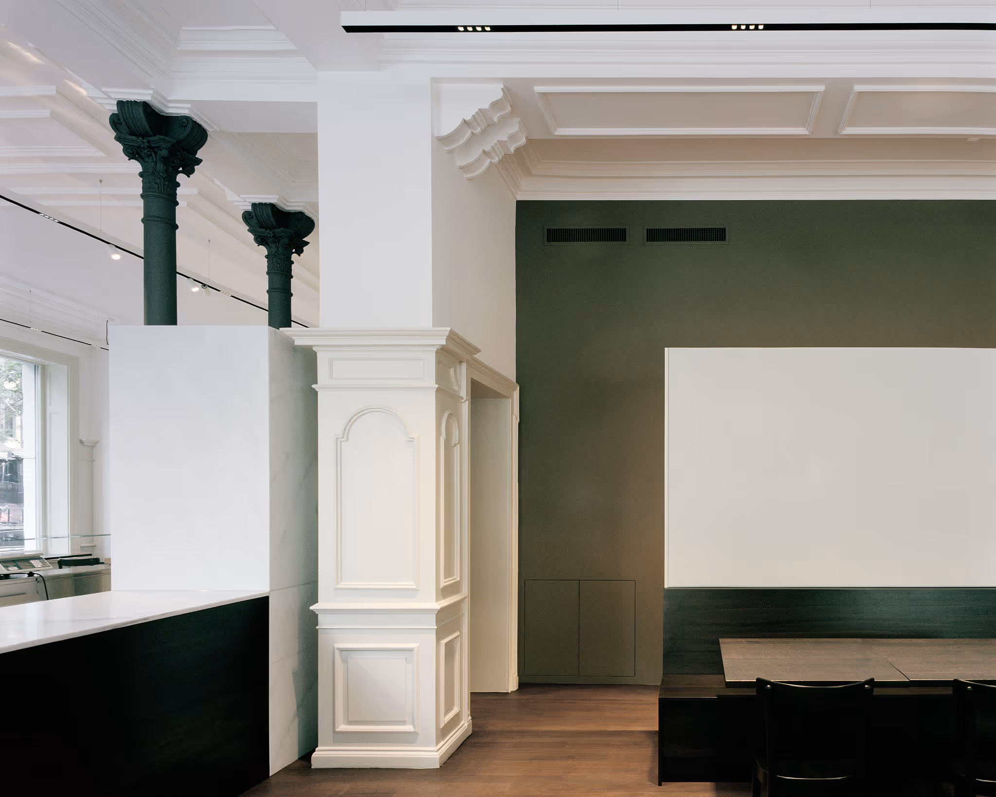 Innenraum mit weißen Säulen, grüner Wand und minimalistischem Design