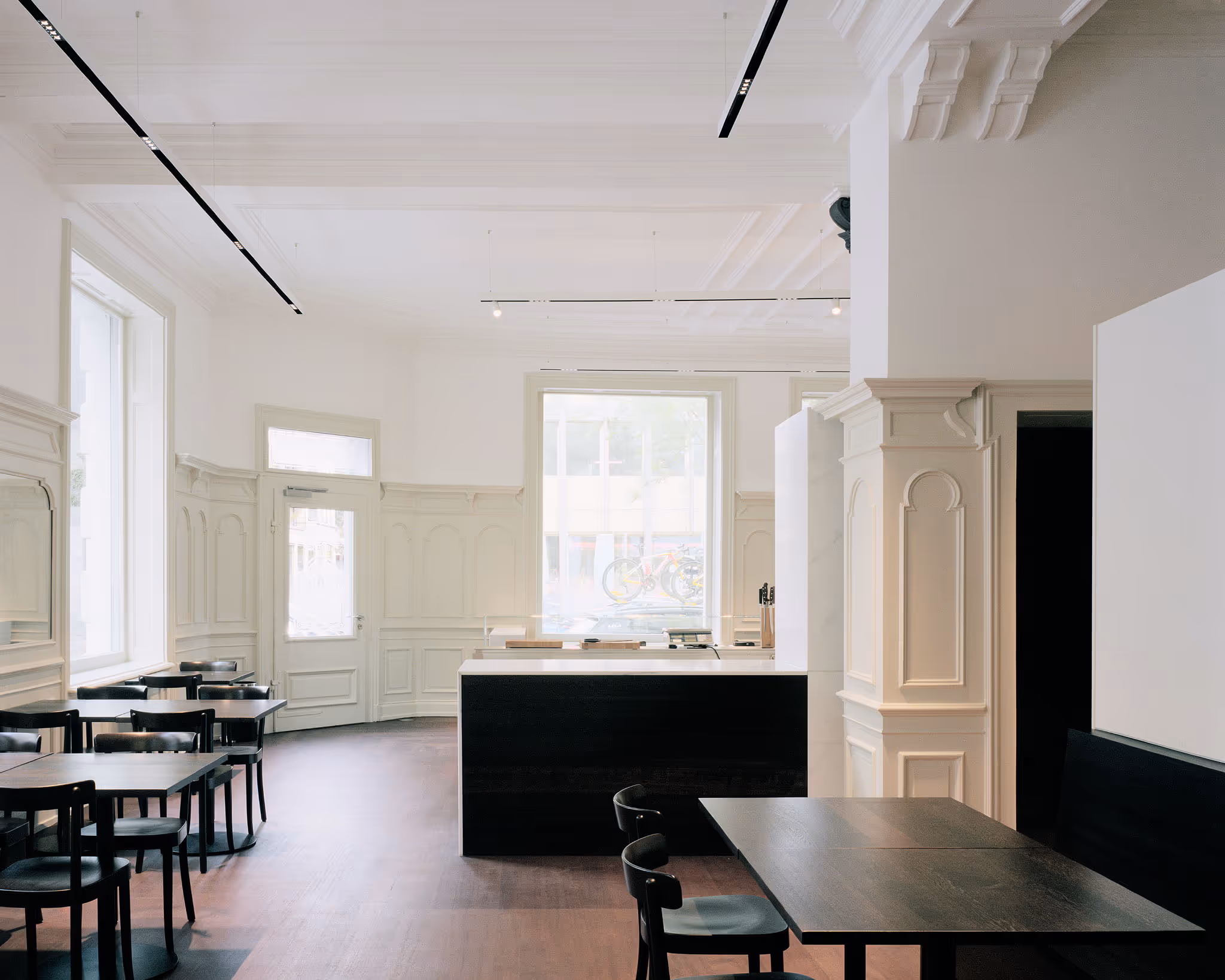 Minimalistisches Café mit weißen Wänden, schwarzen Tischen und Holzboden
