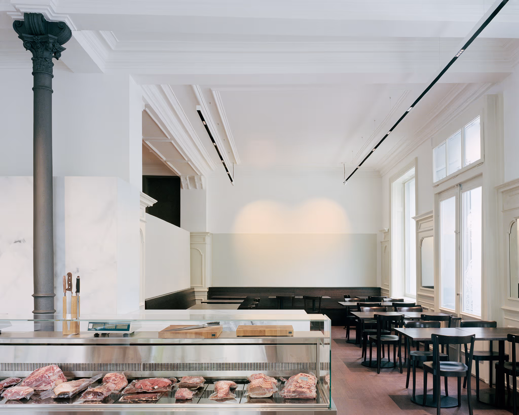 Metzgerei mit Fleischschau, Holztischen und elegantem weißem Interieur