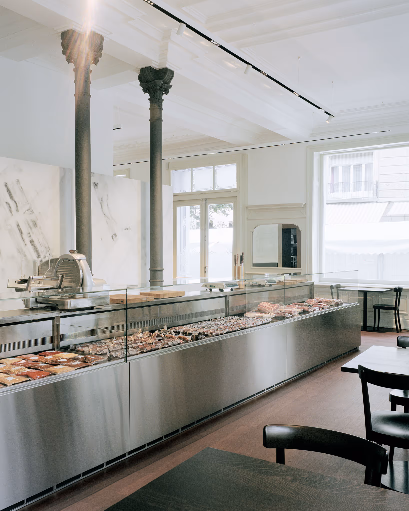 Moderner Fleischmarkt mit Glasvitrine und historischen Säulen in hellem Raum