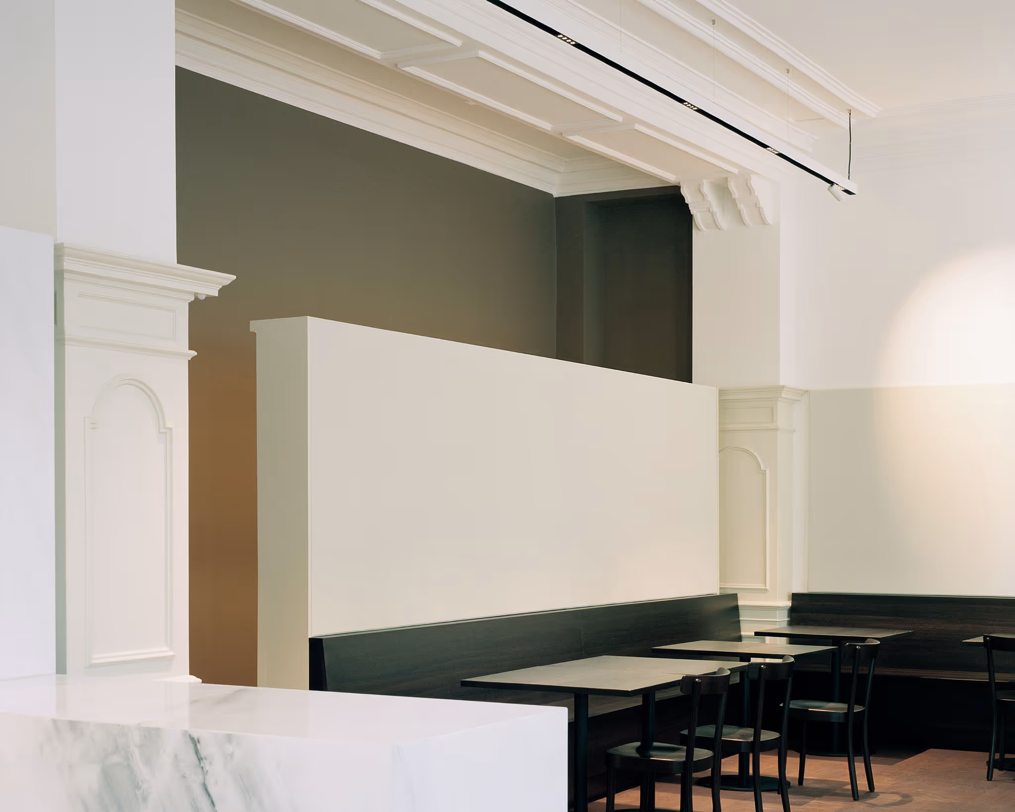 Minimalistisches Café mit weißen Wänden, schwarzen Stühlen und geometrischen Formen