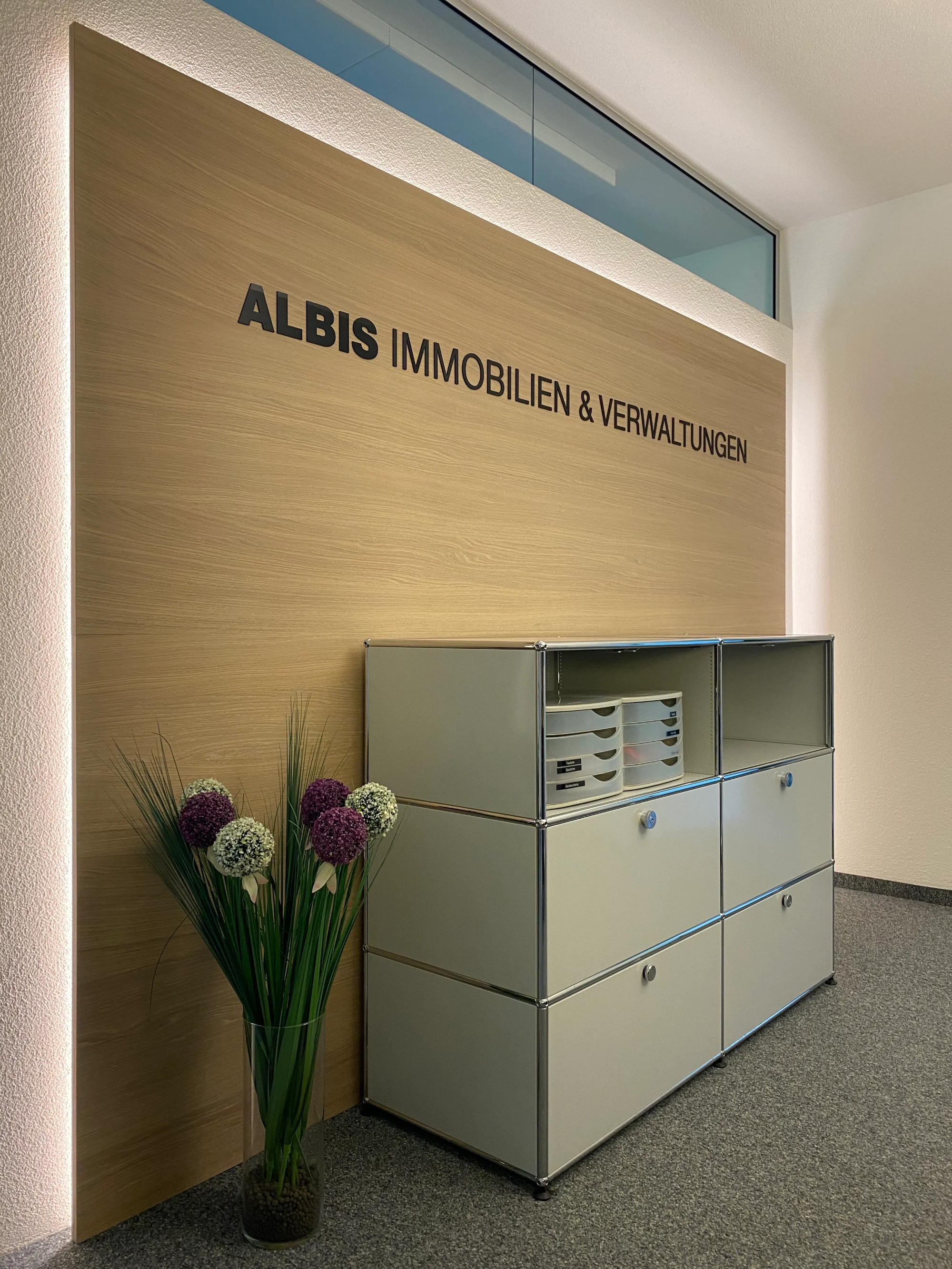 Albis Immobilien Büroeingang mit Metallschrank und Blumen