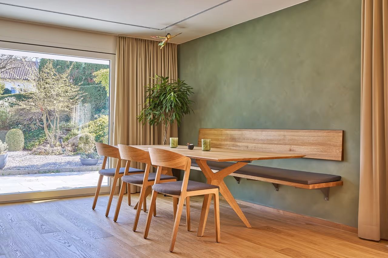 Moderner Essbereich mit Holzmöbeln, grüner Wand und Blick in den Garten