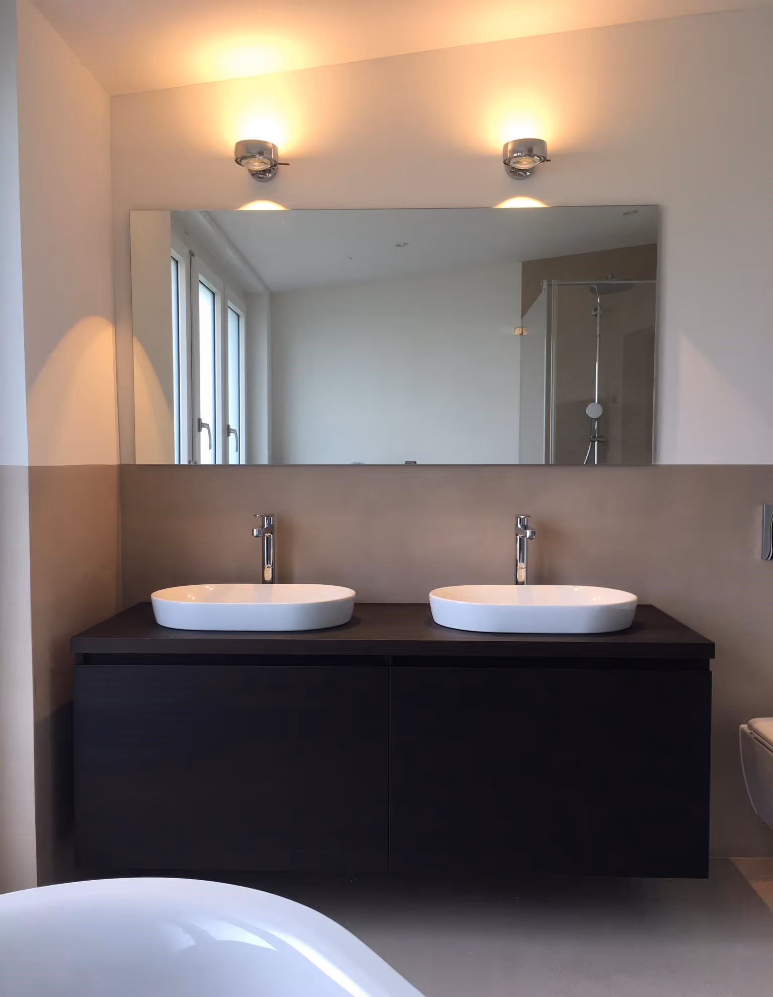 Modernes Badezimmer mit zwei Waschbecken, Spiegel und warmem Licht