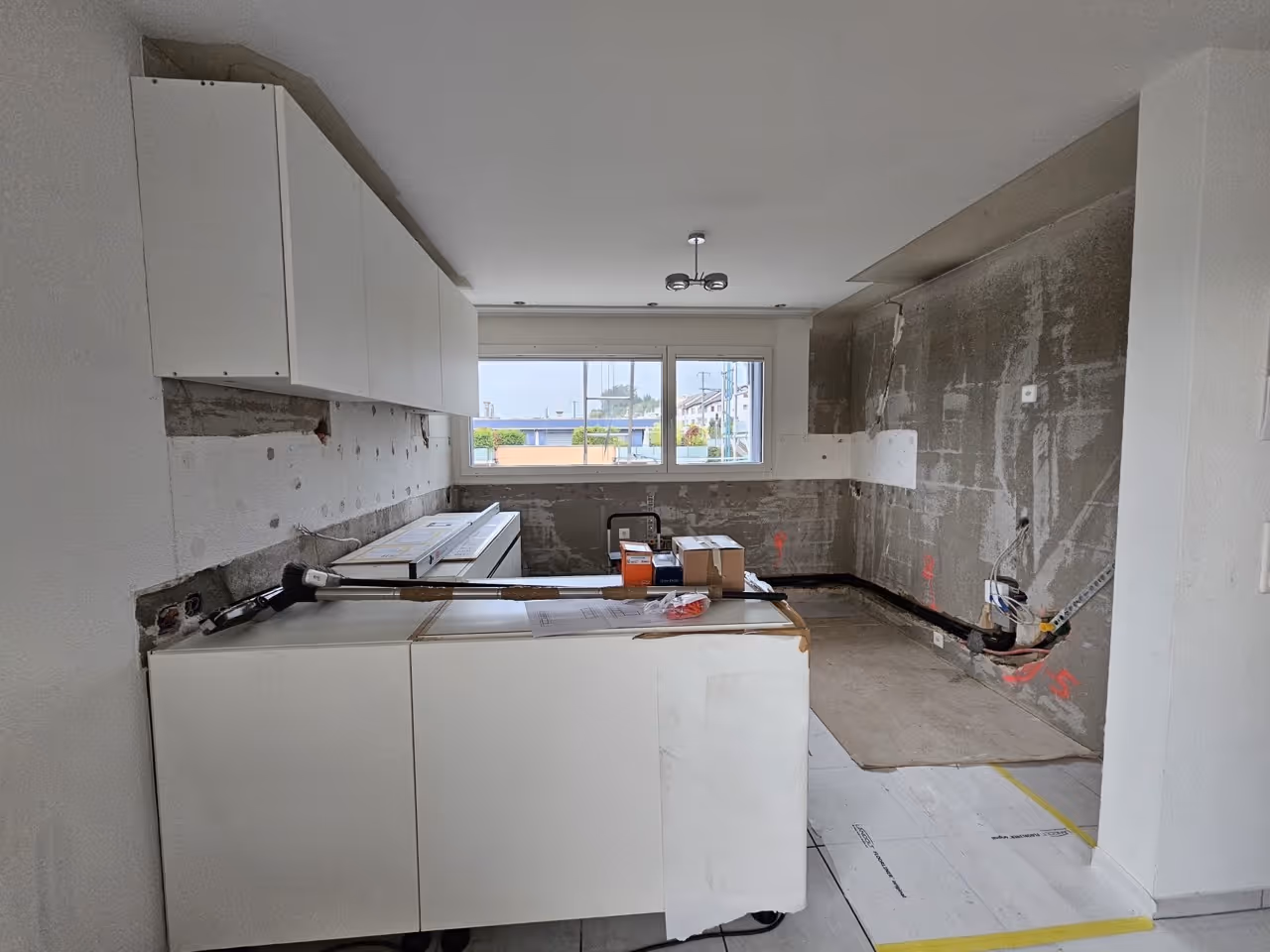 Weiße Küche im Rohbau mit Baustelle und Werkzeugen
