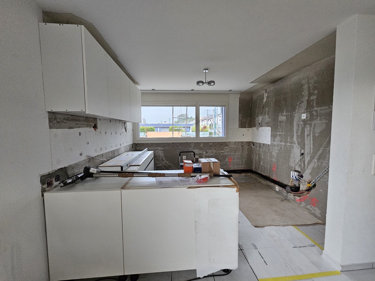 Weiße Küche im Rohbau mit Baustelle und Werkzeugen