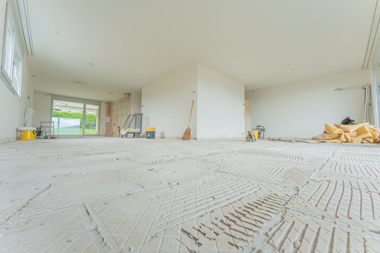 Leerer Raum in Renovierung mit Betonboden und Baugeräten