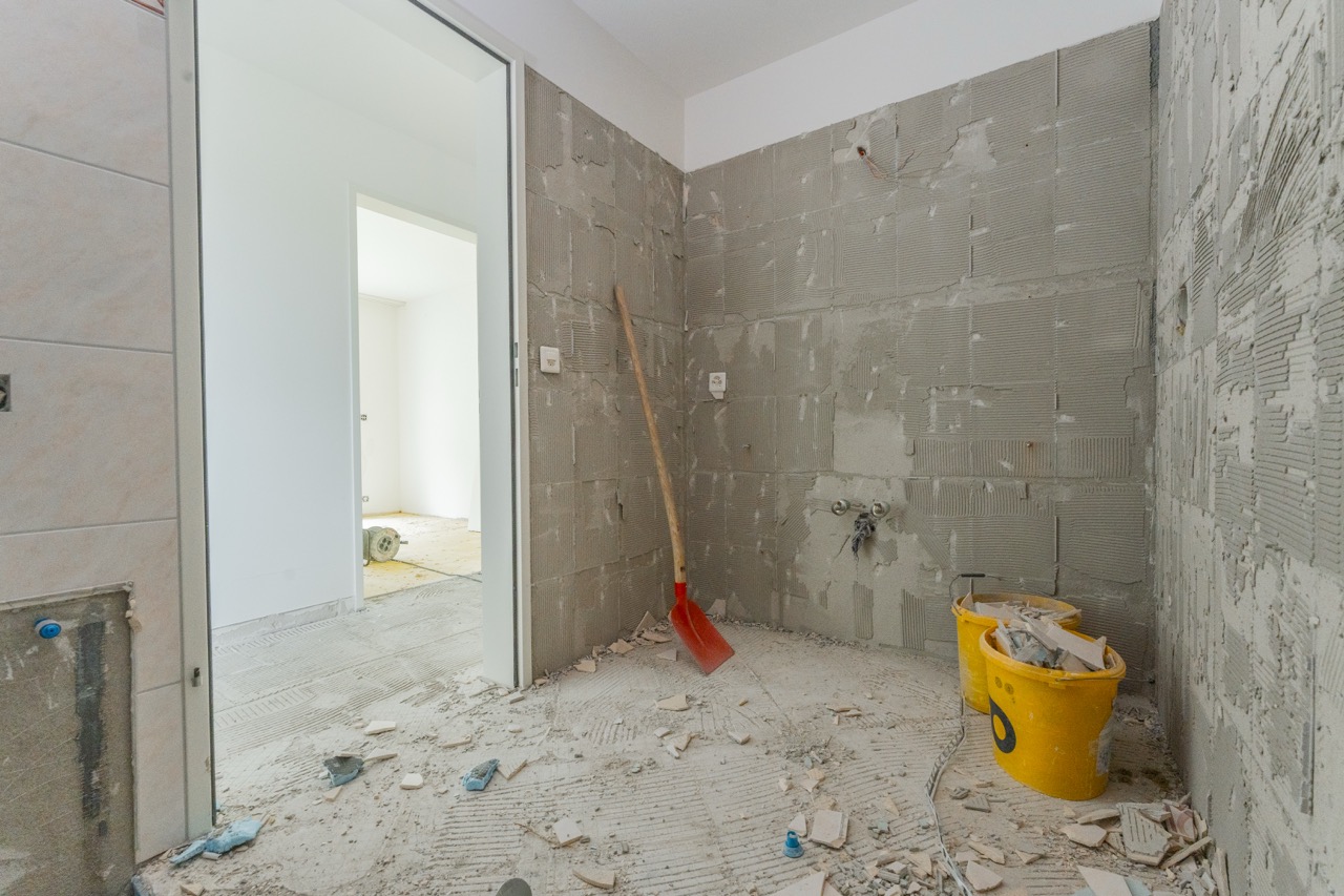 Baustelle mit rotem Besen, gelbem Eimer und Fliesenarbeiten