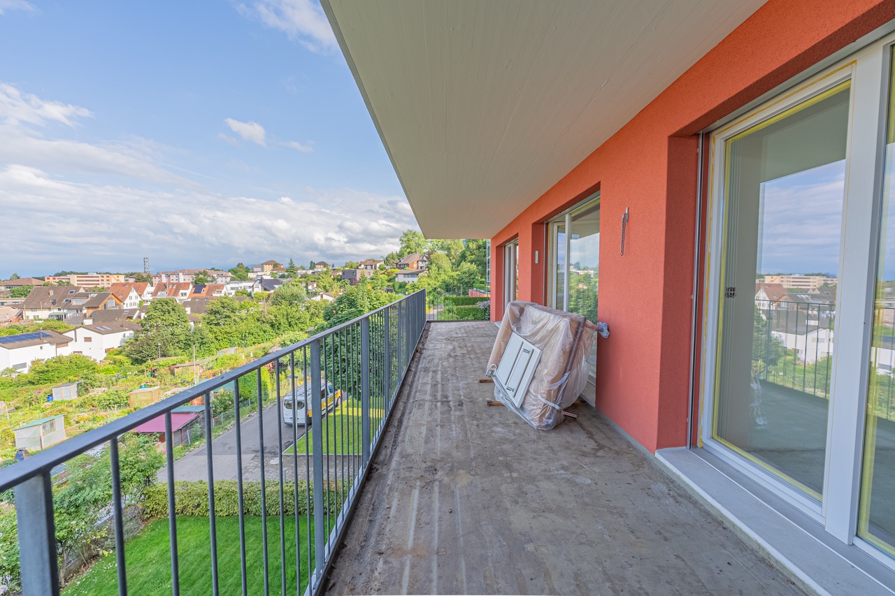 Sonniger Balkon mit Blick auf eine grüne Stadtlandschaft an einem klaren Tag