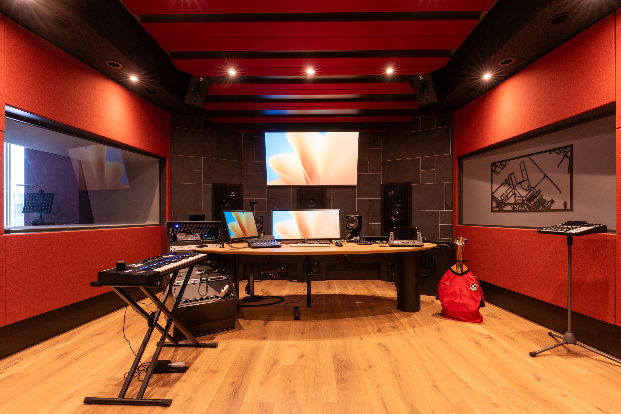 Studio van TFA met rode wanden, een houten regietafel, keyboard en studiomonitoren