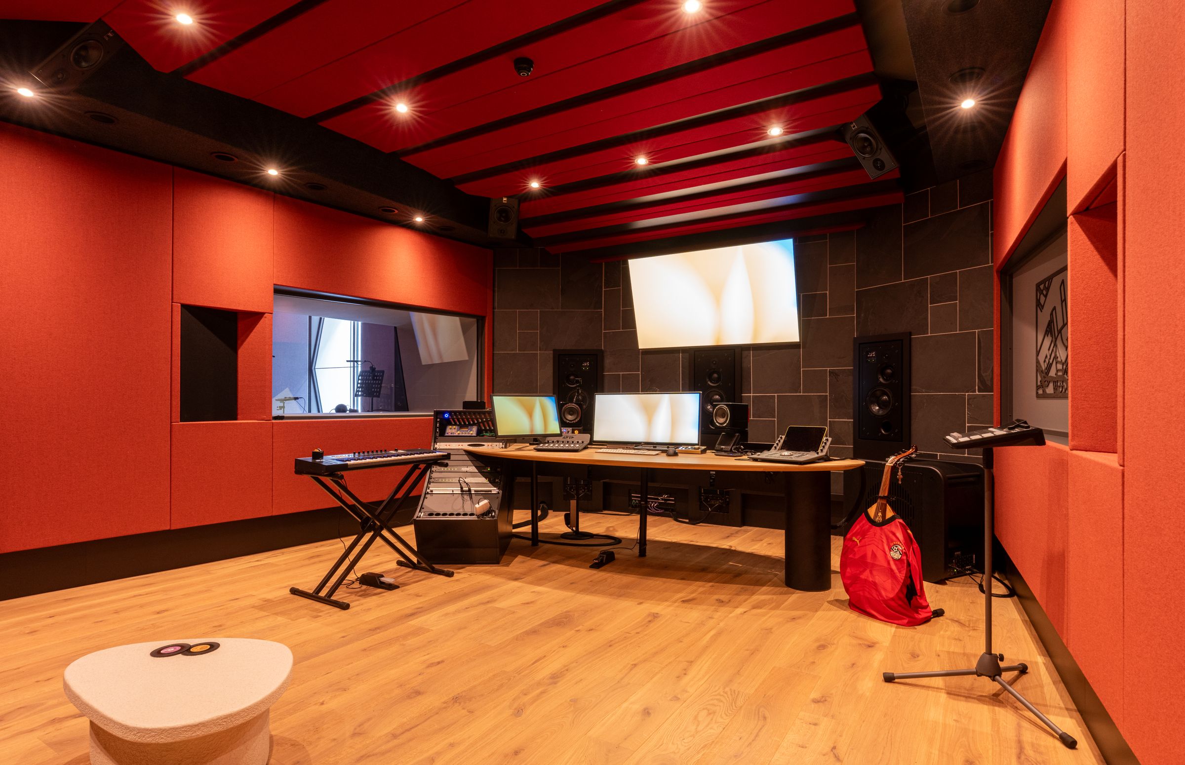 Studio van TFA met rode wanden, een houten regietafel, keyboard en studiomonitoren