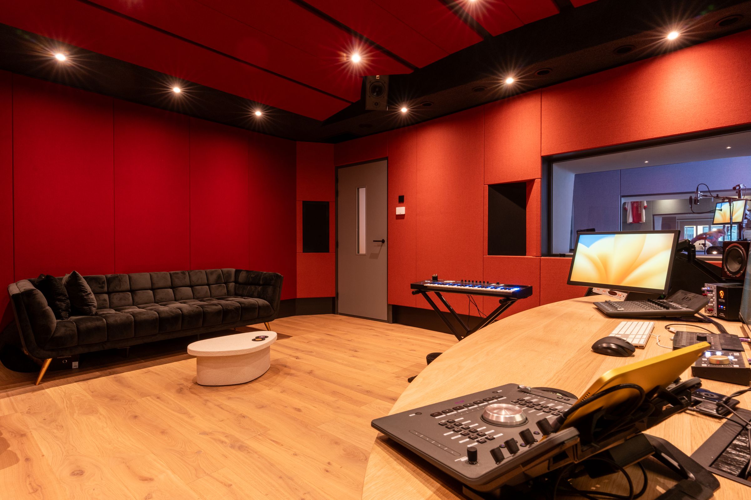 Studio van TFA met rode wanden, een houten regietafel, keyboard en studiomonitoren