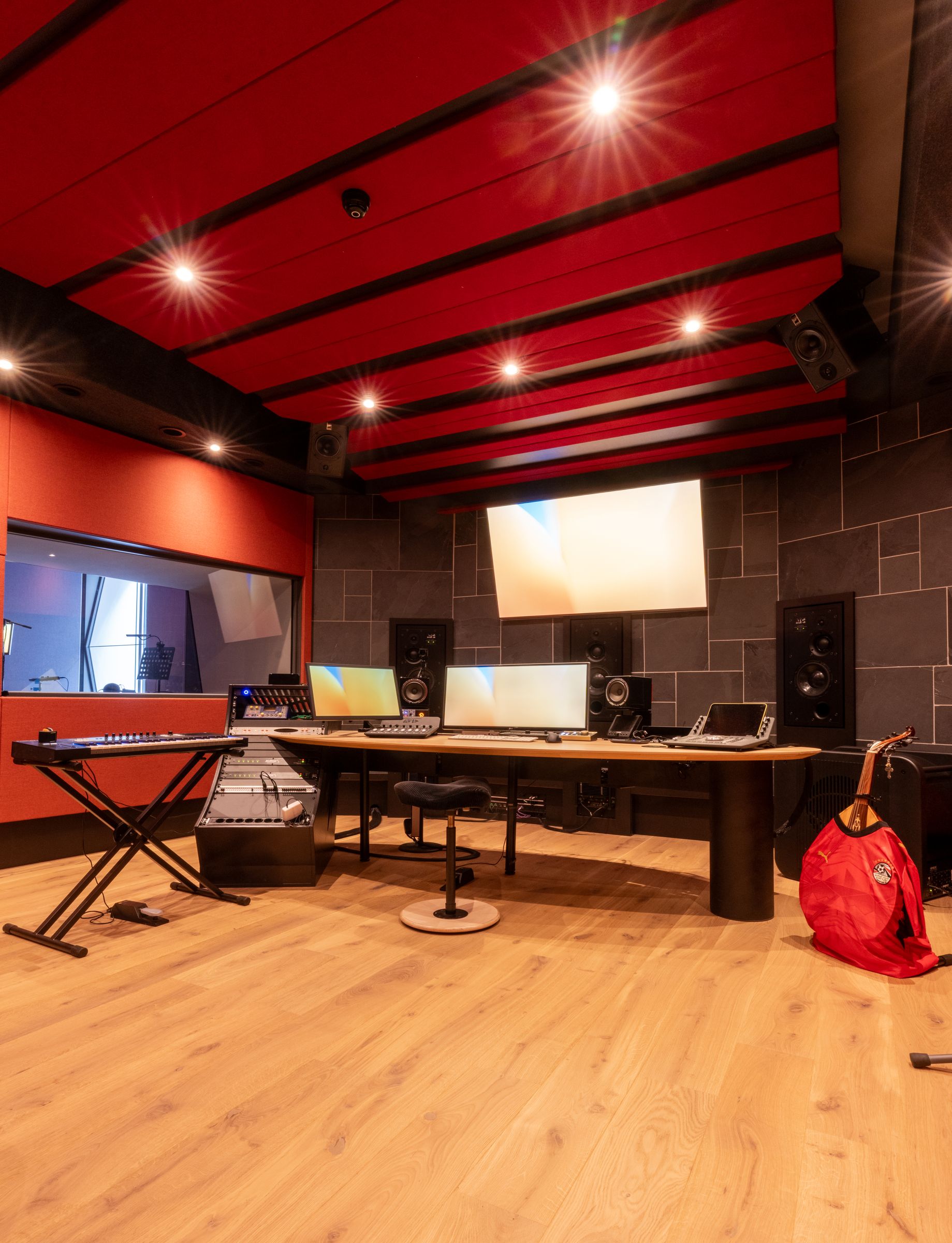 Studio van TFA met rode wanden, een houten regietafel, keyboard en studiomonitoren